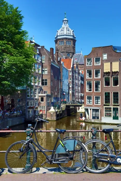  : Bicycles on a canal bridge and the Basilica of Saint Nicholas in Amsterdam, Holland
