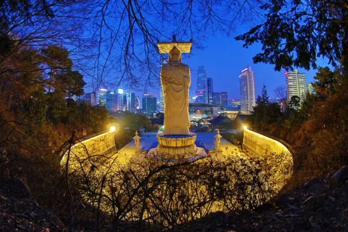  : Buddha statue and the city skyline at Bongeunsa Temple at sunset in Seoul, Korea