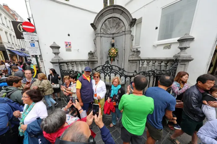  : Crowds of tourists at the Manneken Pis, statue of a boy peeing into a fountain, Brussels