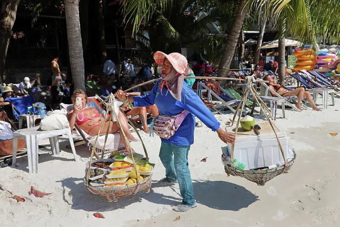  : Food sellers carrying baskets on Sai Kaew Beach on Koh Samet island, Thailand