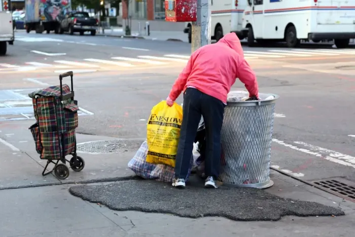  : Homeless person looking through rubbish bins in the street in New York. America