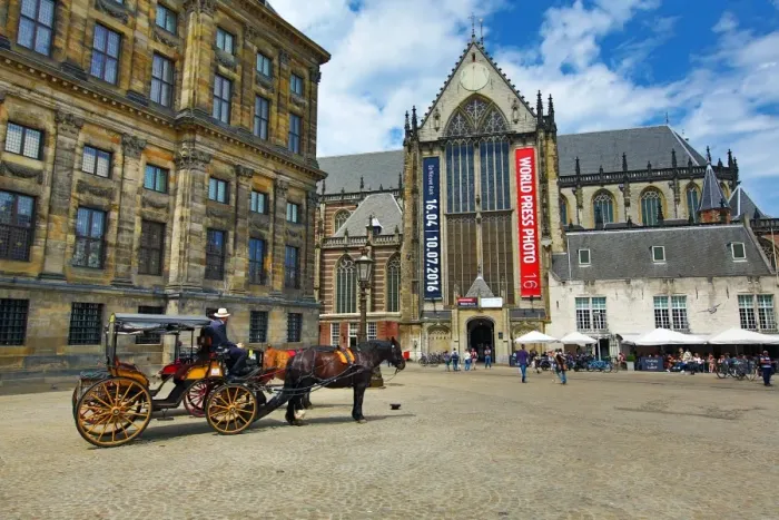  : Horse drawn carriage and the Nieuwe Kerk church in Dam Square in Amsterdam, Holland
