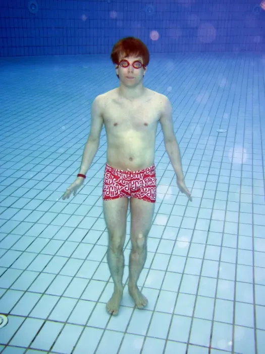  : Man swimming underwater in a swimming pool wearing goggles