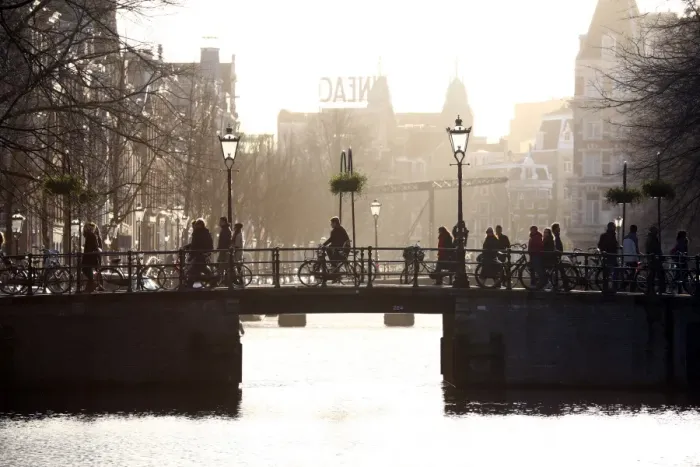  : Silhouette of people and bicycles riding over a bridge over a canal in Amsterdam, Holland