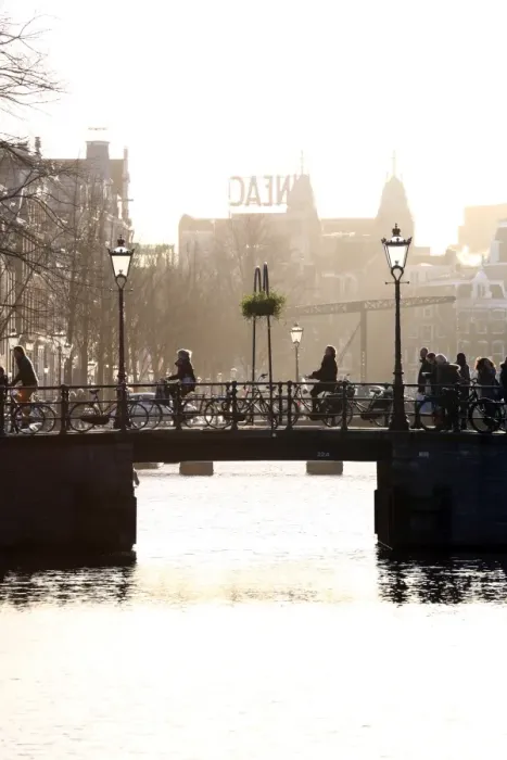 : Silhouette of people and bicycles riding over a bridge over a canal in Amsterdam, Holland