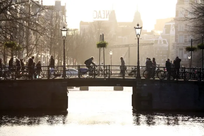  : Silhouette of people and bicycles riding over a bridge over a canal in Amsterdam, Holland