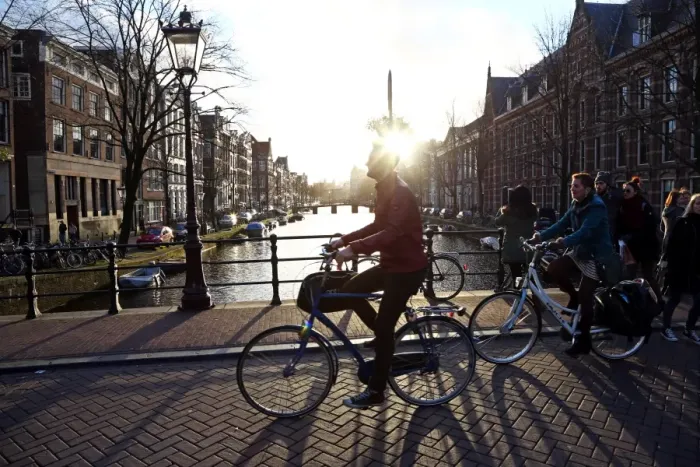 : Silhouette of people and bicycles riding over a bridge over a canal in Amsterdam, Holland : Silhouette of people and bicycles riding over a bridge over a canal in Amsterdam, Holland