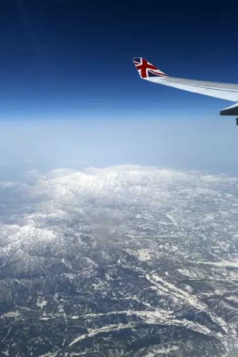  : View out of an aircraft window with mountains and a plane wing