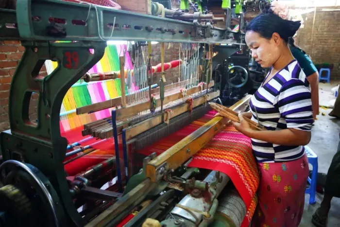  : Weavers weaving yarn using looms in a workshop in Amarapura, Mandalay, Myanmar (Burma)