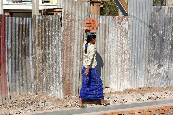 Woman carrying bricks on her head on a building site in Amarapura, Mandalay, Myanmar