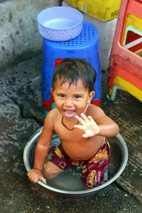  : Young boy bathing in a bowl in the street, Yangon, Myanmar