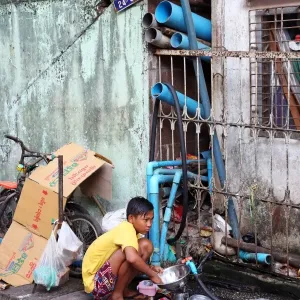 Boy washing dishes in the street, Yangon, Myanmar