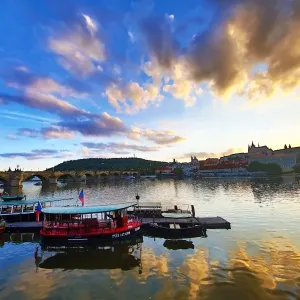 Charles Bridge over the Vltava River and boats at sunset in Prague, Czech Republic