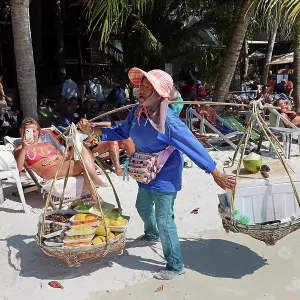 Food sellers carrying baskets on Sai Kaew Beach on Koh Samet island, Thailand