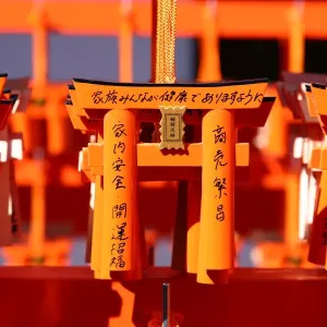 Miniature red torii gates with prayers at Fushimi Inari Shinto shrine in Kyoto, Japan
