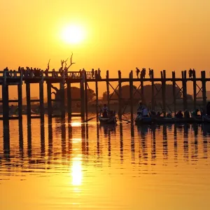People crossing the U Bein Bridge across the Taungthaman Lake at sunset in Amarapura