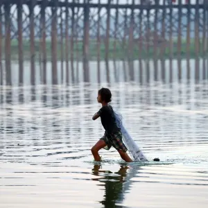 The U Bein Bridge with a fisherman walking across the Taungthaman Lake in Amarapura