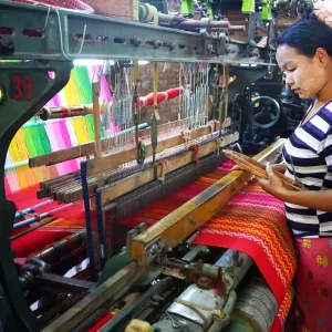 Weavers weaving yarn using looms in a workshop in Amarapura, Mandalay, Myanmar (Burma)