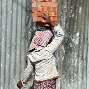 Woman carrying bricks on her head on a building site in Amarapura, Mandalay, Myanmar
