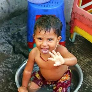 Young boy bathing in a bowl in the street, Yangon, Myanmar