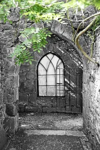 Churches: Arched church window in a stone archway in a chapel with green leaves