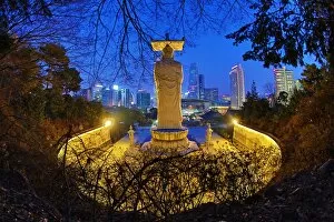 Buddha statue and the city skyline at Bongeunsa Temple at sunset in Seoul, Korea