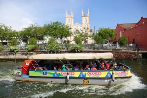 Melaka: Church of St. Francis Xavier and a tourist sightseeing boat on the Sungai Melaka river in Malacca