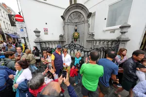 Statues: Crowds of tourists at the Manneken Pis, statue of a boy peeing into a fountain, Brussels