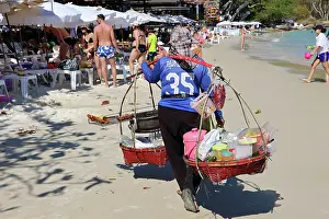 Scene: Food sellers carrying baskets on Phai Bay Beach on Koh Samet island, Thailand