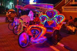 Lighting: Illuminated decorated kitsch cycle trishaw rickshaw with soft toys at night in Malacca