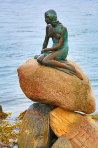 Landmark: The Little Mermaid statue sitting on rocks, Copenhagen, Denmark