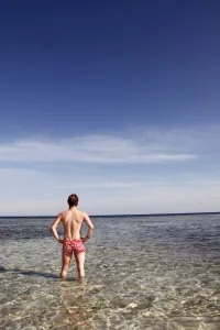 Vacation: Man standing in the sea looking at the horizon