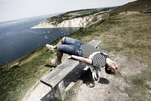 Funny: Man wearing striped T shirt on holiday sitting on a bench