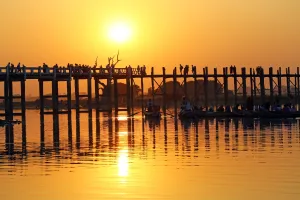 World: People crossing the U Bein Bridge across the Taungthaman Lake at sunset in Amarapura