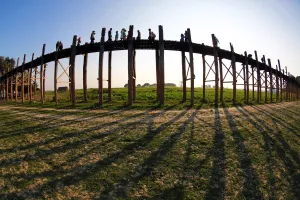 World: Shadows of the U Bein Bridge across the Taungthaman Lake at sunset in Amarapura