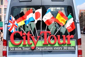 Tourism: Sign with international flags on a City Tour sightseeing bus, Bruges, Belgium