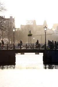 Netherlands: Silhouette of people and bicycles riding over a bridge over a canal in Amsterdam, Holland
