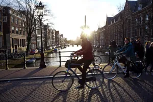 Silhouette of people and bicycles riding over a bridge over a canal in Amsterdam, Holland