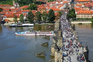 Crowds: Tourists walking over the Charles Bridge over the Vltava River with a boat sailig