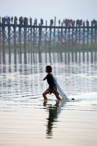 World: The U Bein Bridge with a fisherman walking across the Taungthaman Lake in Amarapura