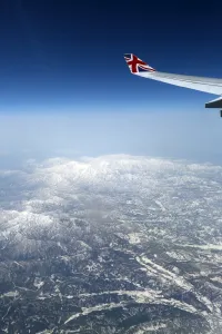 Flying: View out of an aircraft window with mountains and a plane wing