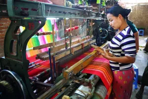 Industry: Weavers weaving yarn using looms in a workshop in Amarapura, Mandalay, Myanmar (Burma)